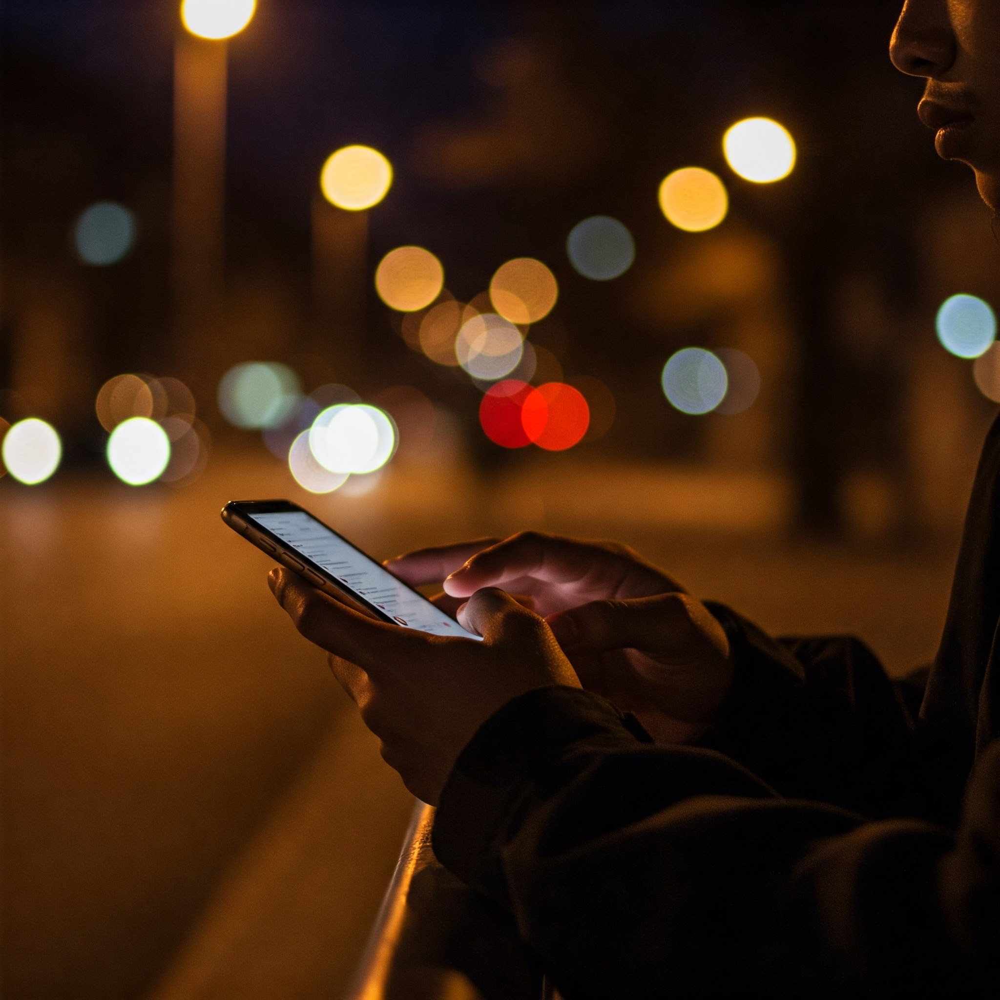photo of Person Using Smartphone at Night in City